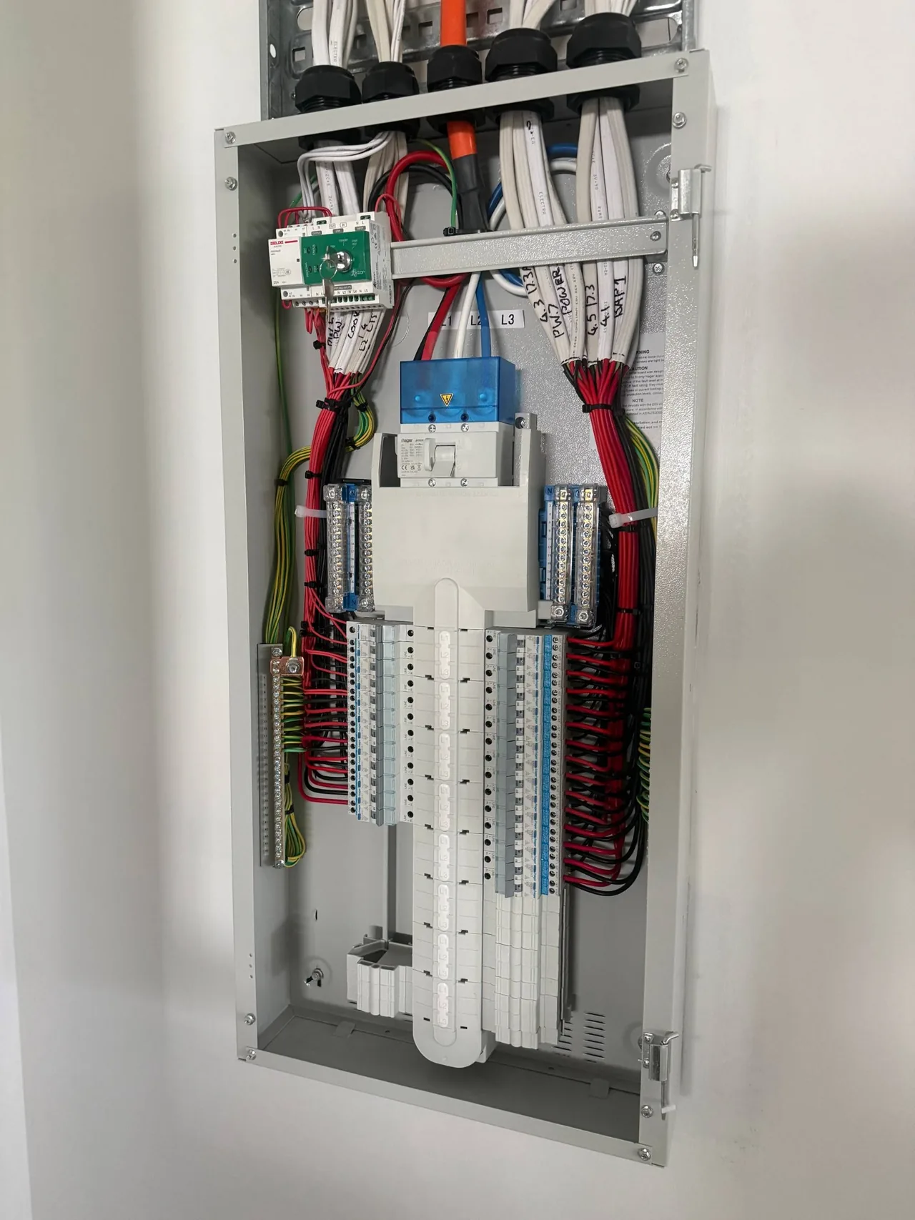 Open commercial electrical switchboard with labelled wiring and rows of circuit breakers