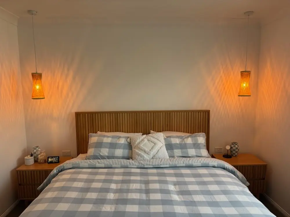 Warm bedside wall lights installed above a timber bedhead