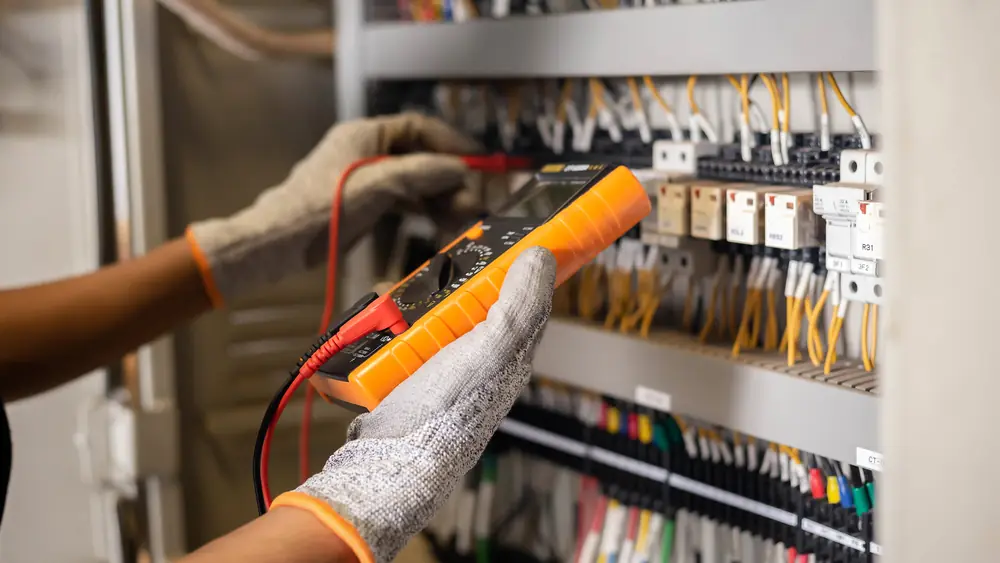 Multimeter being used to test wiring inside an electrical control panel