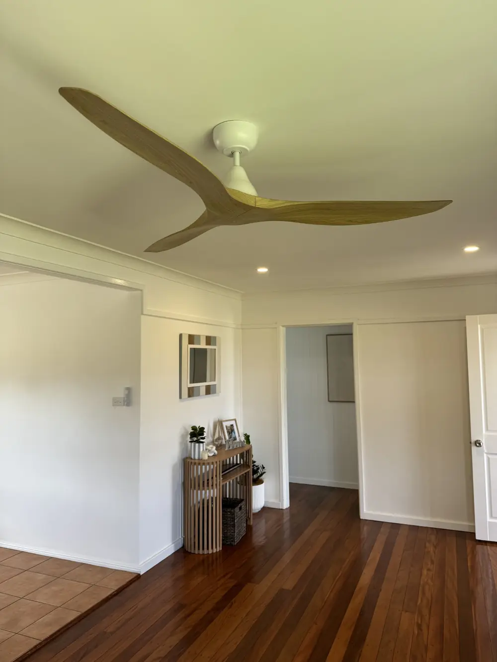 Timber-bladed ceiling fan and recessed lights above a living room