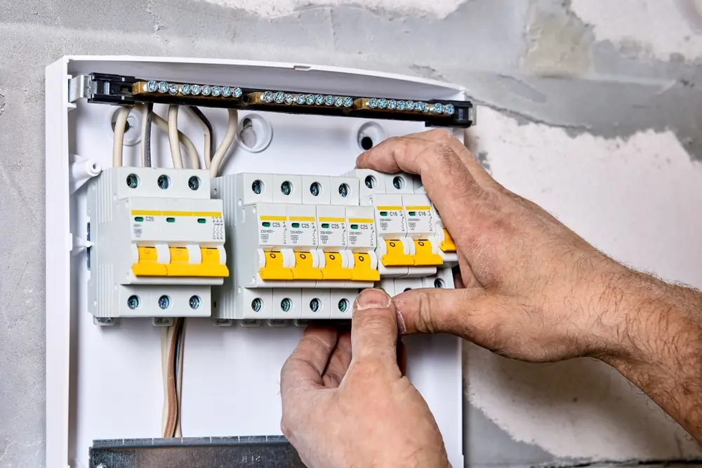 Hands checking circuit breakers inside an open switchboard