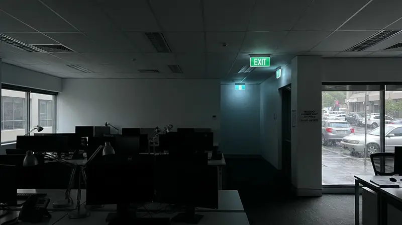 Dark office interior with illuminated emergency exit signs during a power outage