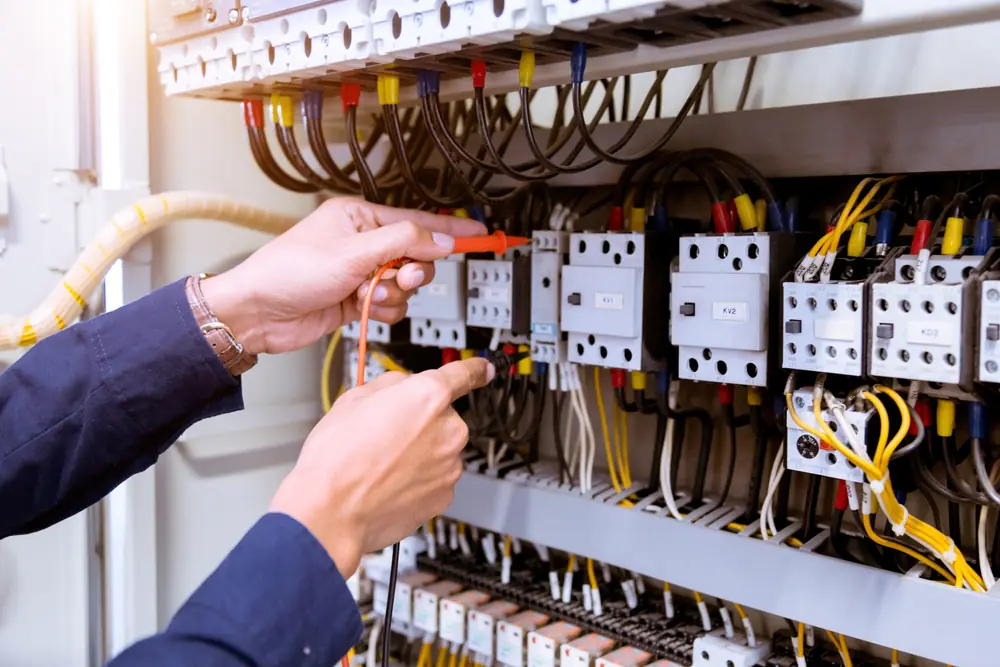 Hands carrying out electrical work inside a commercial control panel