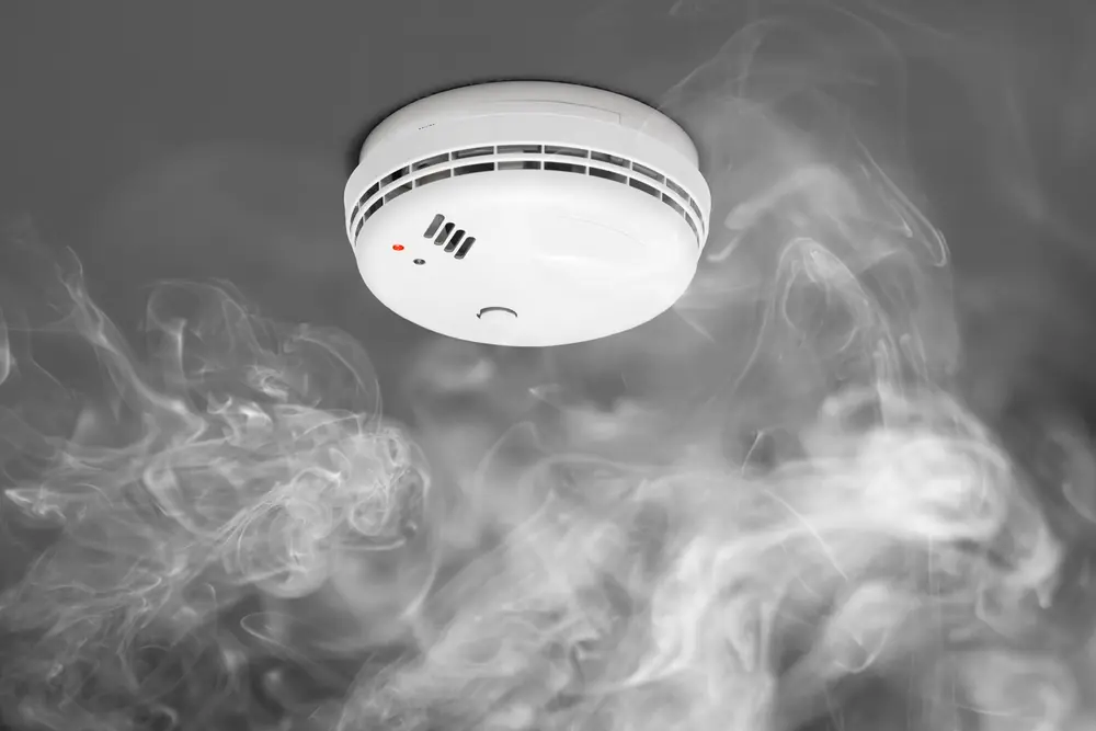 Ceiling-mounted smoke detector surrounded by smoke