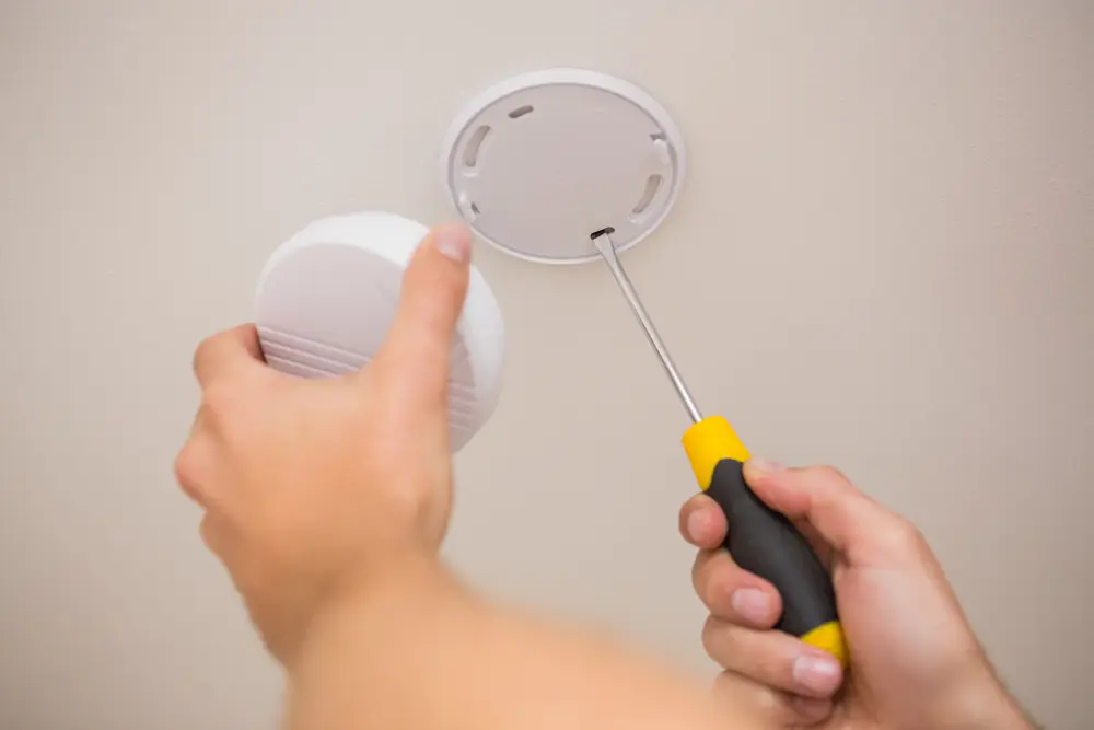 Smoke detector being removed or installed on a ceiling mounting base