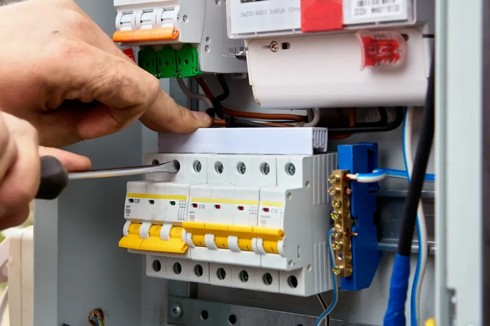 Switchboard wiring and circuit breakers being adjusted during electrical work